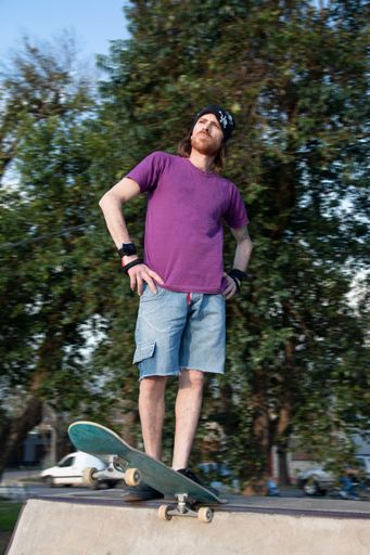 A vertical of a young Argentinian skateboarder posing in the park