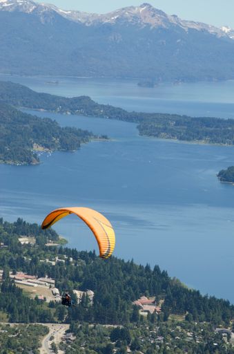 An extreme sport, paragliding flying landscape city of Bariloche, lake Nahuel huapi and mountains in vertical with copy space