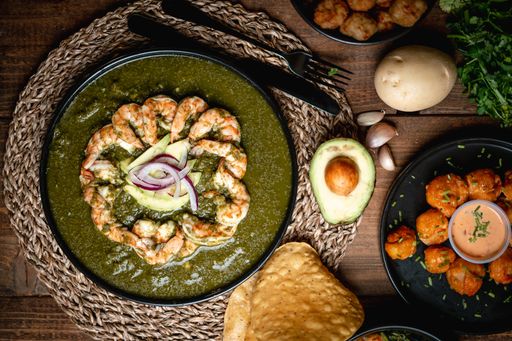 A top view of the delicious appetizing shrimps served on a black plate on a wooden table at a restaurant