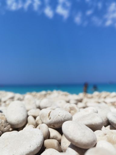 A selective focus shot of white pebbles at a beach on a sunny day in summer