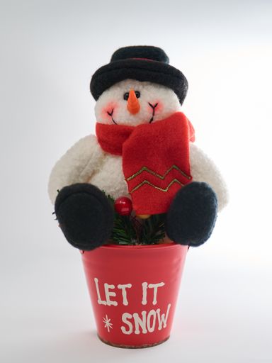 A closeup of a fluffy snowman toy on a red pot