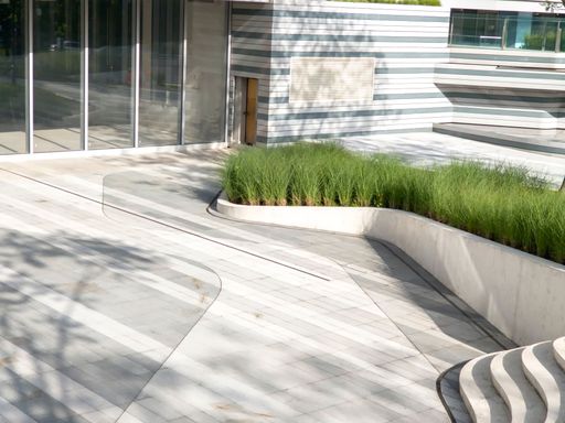 A modern architectural exterior with sleek lines and green landscaping, with glass windows