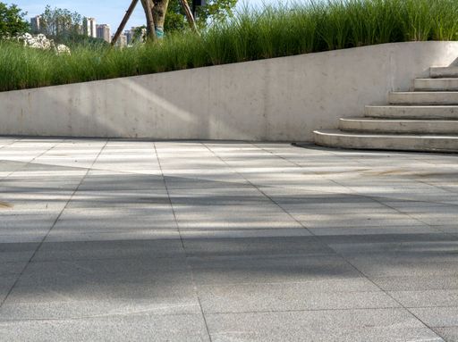 Paved area with concrete steps leading up to a grassy slope, suggesting a modern urban landscape design.