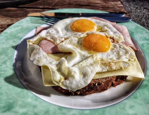 A closeup shot of morning breakfast with fried eggs, bacon, cheese, and toast in a plate.