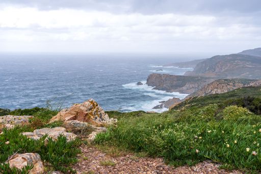 Scenic coastal view of rocky cliffs and ocean waves under a cloudy sky at Cabo da Roca, Portugal.