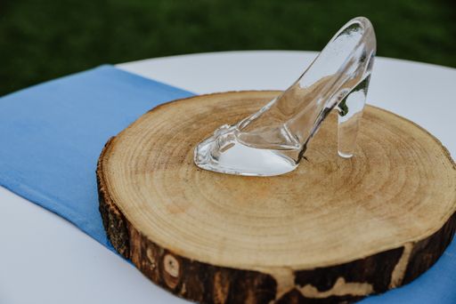 A closeup shot of a crystal slipper on a sliced wooden circle on a blue and white tablecloth