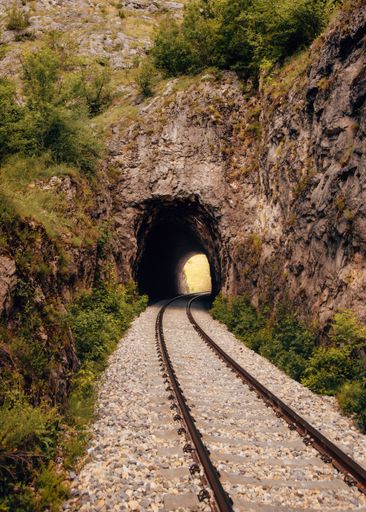 A vertical shot of train tracks and a tunnel surrounded by cliffs