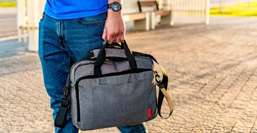A closeup shot of a male holding a textile briefcase for a laptop