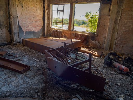 Anglesey, Wales, UK, 05-17-2025: Abandoned derelict room with debris and broken window, revealing sunlight outside.