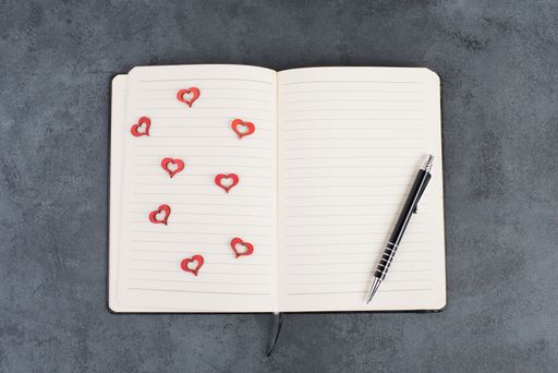 Empty booklet with wooden hearts and a pen