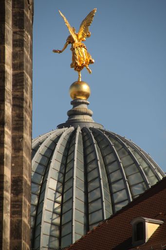 Golden angel statue atop the dome of Dresden Academy of Fine Arts against a clear blue sky.