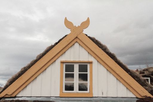 A closeup shot of the roof of a white building with the cloudy sky in the background in Iceland