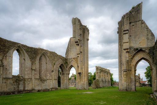 Ruins of Glastonbury Abbey in Somerset, England, showcasing medieval architecture against a cloudy sky.