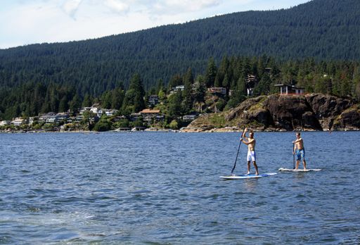 Two men sup boarding on water in Belcarra Park in Vancouver, British Columbia, Canada