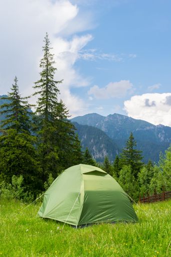 A green tent installed in the wild mountain scenery