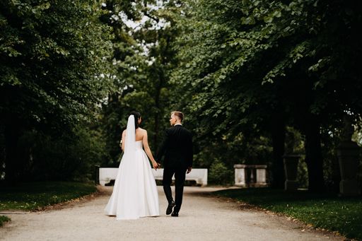 A beautiful view of a Caucasian (white) bride and groom walking together in a forest in Lithuania