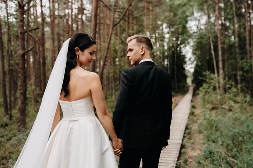 A beautiful shot of the back of Caucasian (white) bride and groom together in the forest in Lithuania