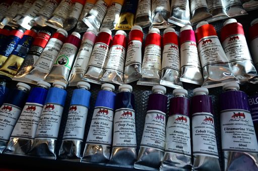 Colorful oil paint tubes on textured surface displaying various hues and brands