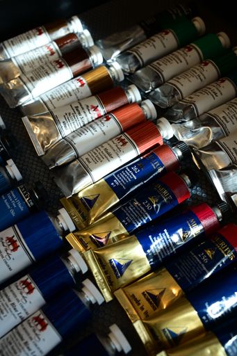 An assortment of colorful oil paint tubes displayed on a textured surface, showcasing various hues and brands.