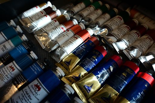 An assortment of colorful oil paint tubes displayed on a textured surface, showcasing various hues and brands.