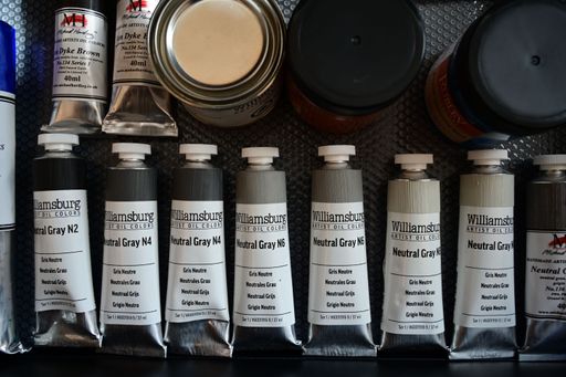 Colorful oil paint tubes on a textured surface displaying various hues and brands