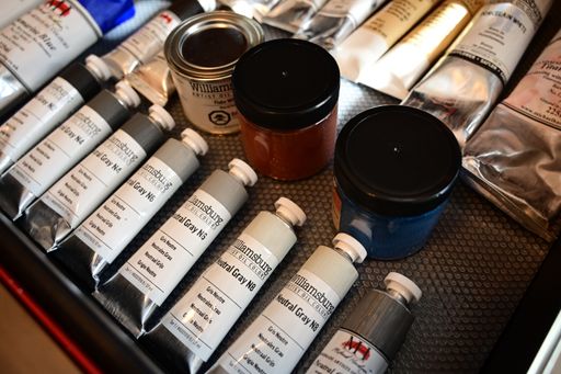 An assortment of colorful oil paint tubes displayed on a textured surface, showcasing various hues and brands.