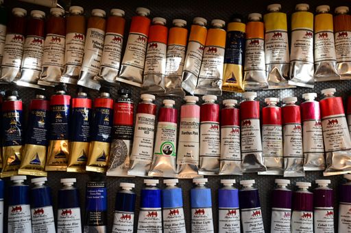 An assortment of colorful oil paint tubes displayed on a textured surface, showcasing various hues and brands.