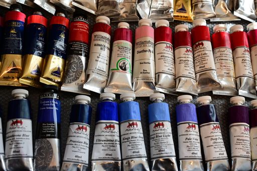 An assortment of colorful oil paint tubes displayed on a textured surface, showcasing various hues and brands.