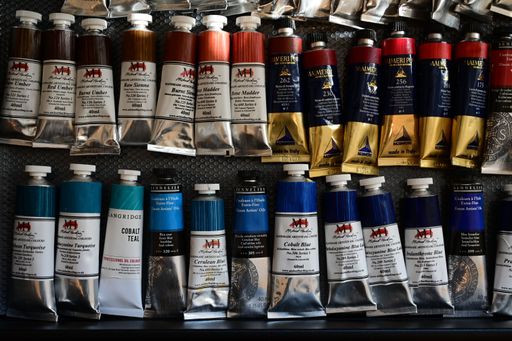 Colorful oil paint tubes on a textured surface showcasing various hues and brands