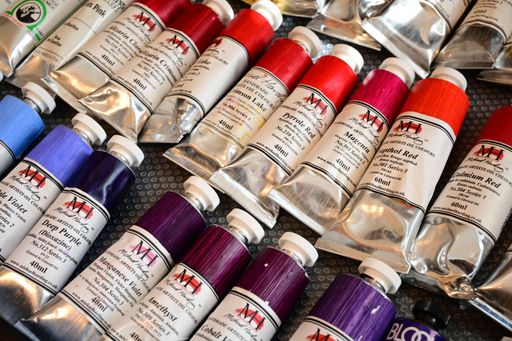 A collection of vibrant artist oil paint tubes arranged on a textured surface, showcasing a variety of colors.