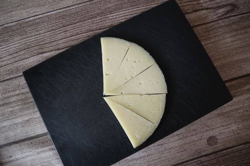 A top view of a five slices of a cheese on a black plate on a  wooden table