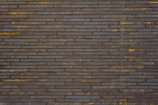 Vintage wall of long worn bricks with yellow bald spots. Industrial designer background.
