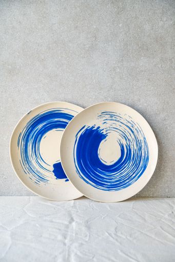 The two ceramic plates with blue swirl patterns on a textured surface, creating a minimalist display