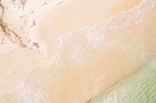 idyllic beach landscape: clear turquoise water meeting a vast stretch of sand aerial drone zenithal view