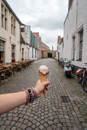 Woman holding an ice cream against medieval cityscape in Bruges, Belgium