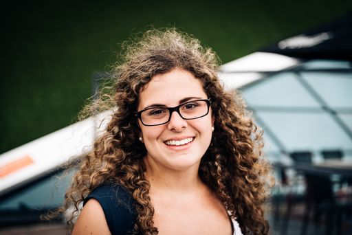 Close up Happy Young Woman, Wearing Eyeglasses, with curly hair, Showing Toothy Smile at the Camera Against city Background.