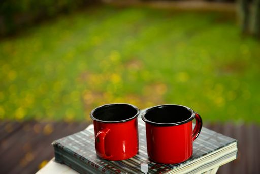 The red coffee cups on top of a book in a yard