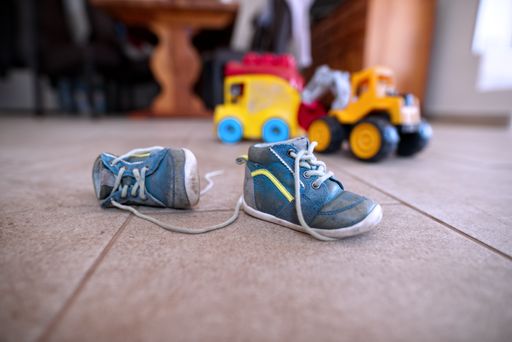 A closeup shot of small blue baby sneakers with a toy in the background