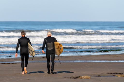 A rear view of men holding surfboards over the head by Ventura Beach