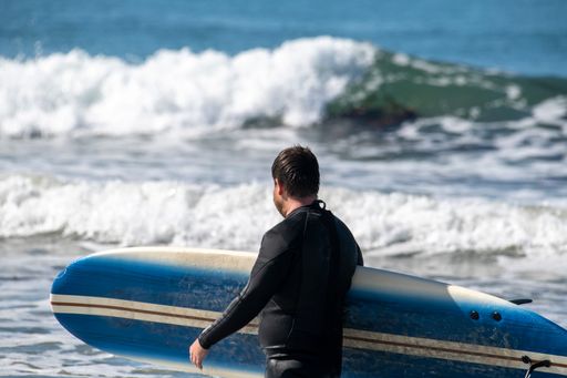 A side view of a man holding a surfboard by Ventura Beach
