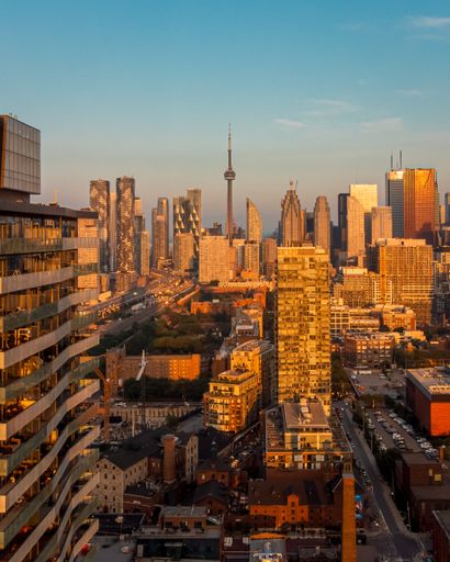 Aerial view of Toronto skyline at sunset with CN Tower and modern skyscrapers under a clear sky.
