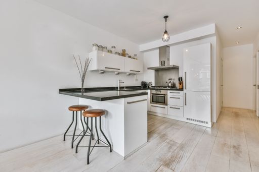 A cozy kitchen with modern white furniture in a minimalist style apartment