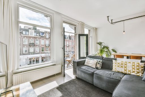 A cozy living room with big windows facing another residential building