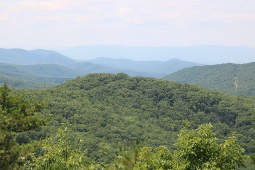 A beautiful top view of mountains covered by forest with cloudy sky in the background