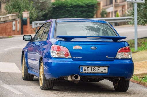 Rear view of a blue Subaru Impreza Facelift Hawkeye, 2nd generation, parked on a street with gold wheels and a spoiler