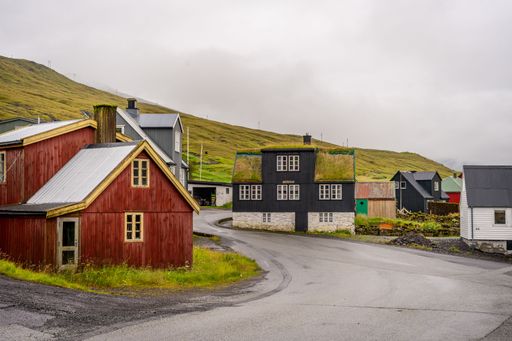 Colorful houses with grass roofs in a scenic village in the Faroe Islands under a cloudy sky.