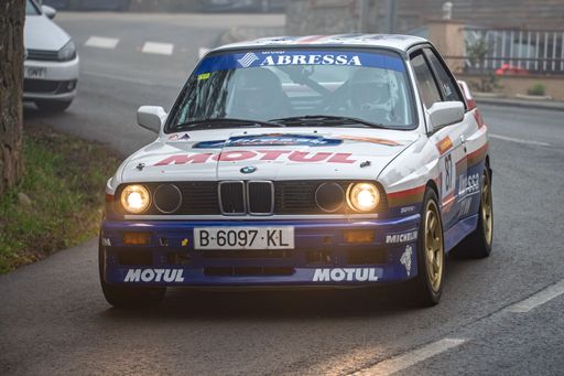 BMW M3 E30 racing in foggy conditions at the 73 Rally KH7 Costa Brava, driven by Alex Dude Alvarez and Dani Muntadas Busquet.
