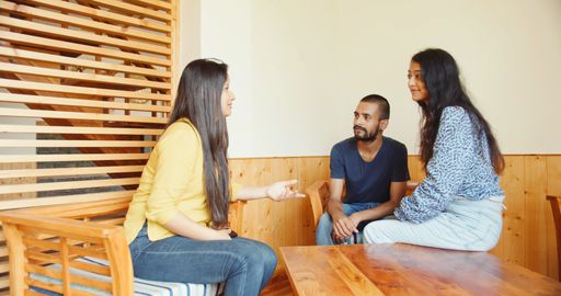 A group of Indian friends sitting in a living room, talking and laughing