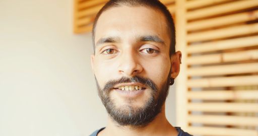 An Indian young guy standing indoors, looking at the camera