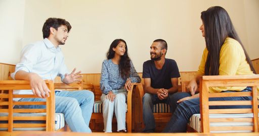 A group of Indian friends sitting in a living room, talking and laughing